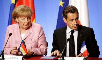 German Chancellor Angela Merkel and French President Nicolas Sarkozy  listen to questions Saturday in Paris.  (Associated Press / The Spokesman-Review)