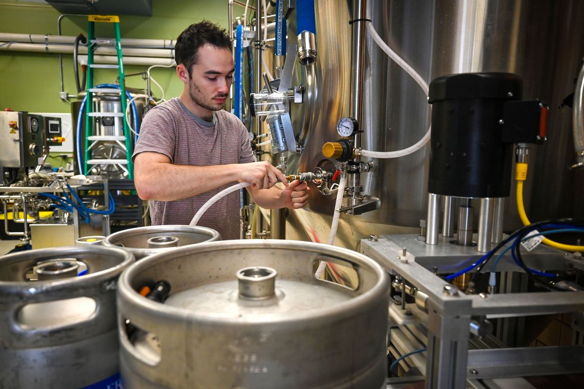 Charlie Thudium, head brewer at Common Language Brewery Company, demonstrates how he hooks up a carbon dioxide feed line to a fermentation tank that is producing a fresh hop West Coast IPA, Wednesday, Sept. 21, 2022 in Spokane. There is a national shortage of carbon dioxide gas that is used to pressurize lines, kegs and provide the very bubbles that makes a brew a beer.  (DAN PELLE/THE SPOKESMAN-REVIEW)