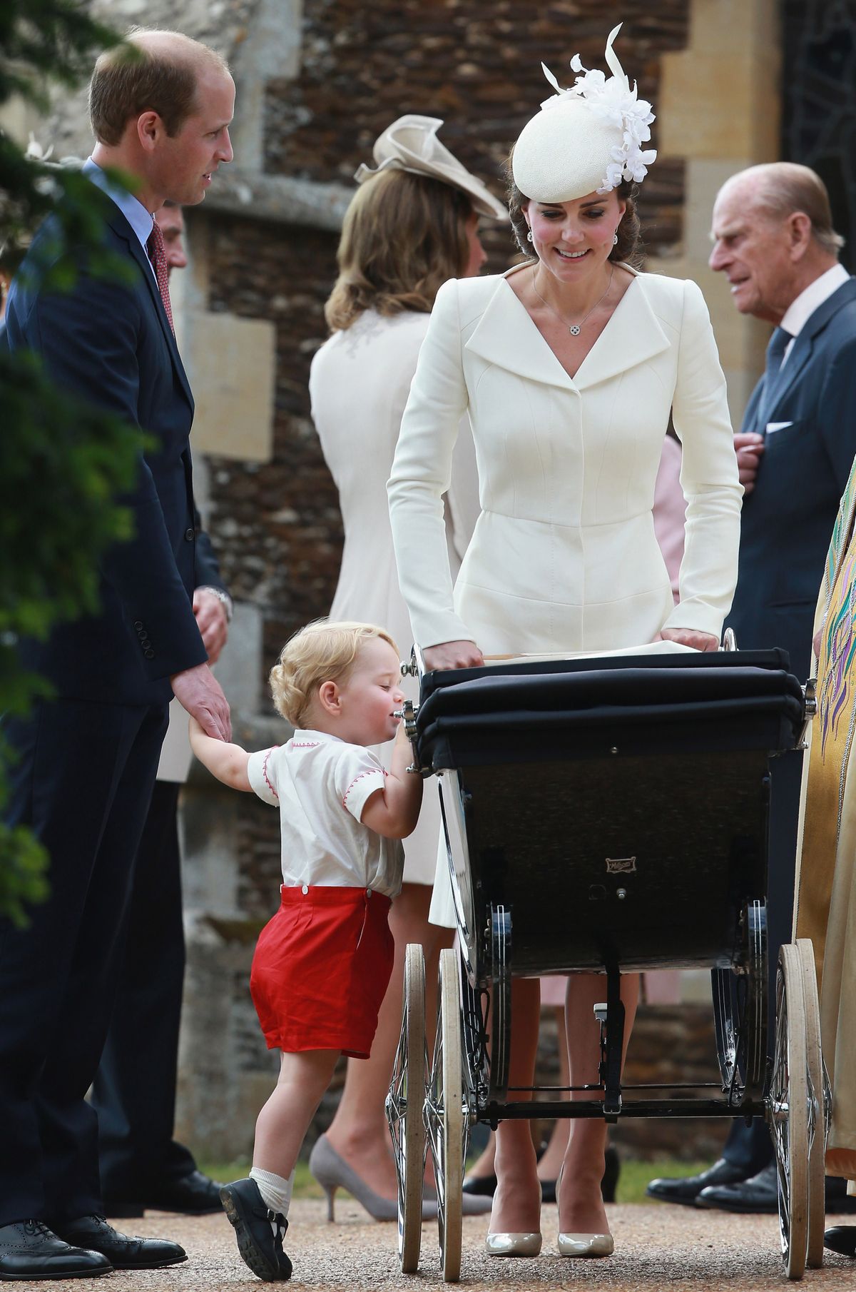 Prince George of Cambridge looks into the pram carrying his sister Princess Charlotte, pushed by Kate the Duchess of Cambridge, with Prince William after the christening Sunday on the Sandringham Estate. (Associated Press)