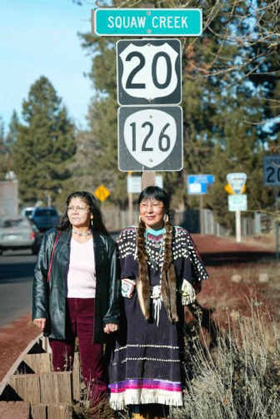 
Colleen Roba, left, and Olivia Wallulatum, of the Confederated Tribes of the Warm Springs, pose next to highway signs, including one for Squaw Creek in Sisters, Ore. Olivia Wallulatum says she has spent much of her life trying to forget the slur 