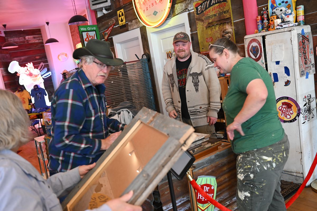 Local artist Chris Bovey smiles as his wife, Liz Bovey, right, and local craftsman Curtiss Larson and his wife, Laine Larson, left, drop off custom frames made from reclaimed barnwood for Bovey’s prints at the new site of Vintage Print + Neon on April 15 inside the historic Boulevard Building at Indiana Avenue and Monroe Street in Spokane.  (Tyler Tjomsland/The Spokesman-Review)