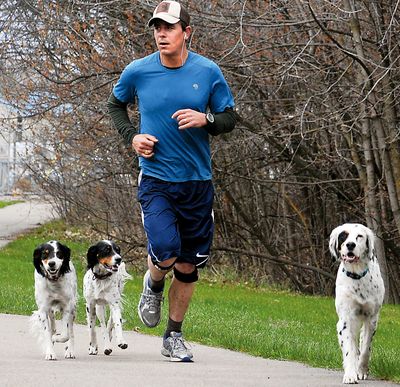 Ben Laster runs with his dogs, from left, Penny, Daisy-Nay and Chowdie, in Kalispell. (Associated Press)