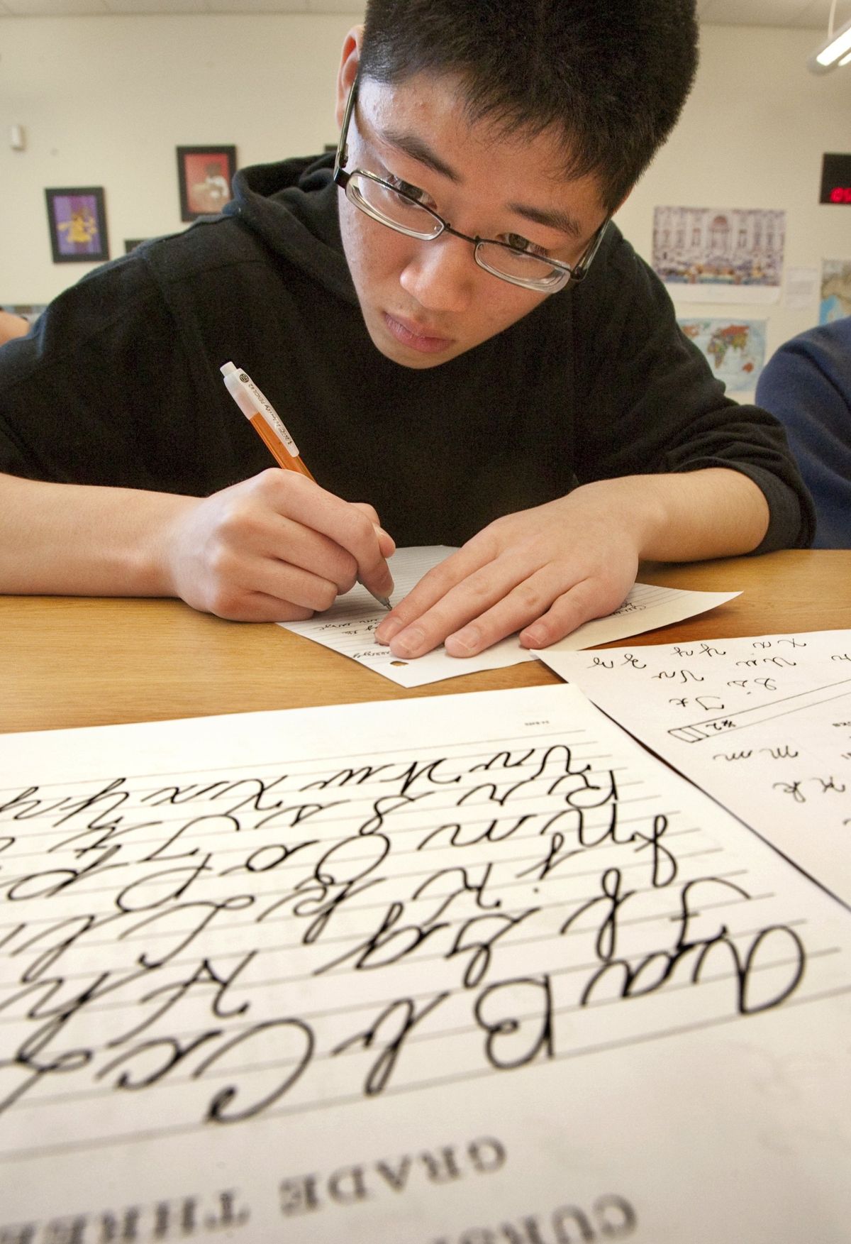Kevin Tang, a senior at Roosevelt High School, is among the students receiving a one-hour refresher lesson in cursive writing on May 20 in Seattle. Tang  took the refresher at the suggestion of Latin teacher Nora MacDonald.