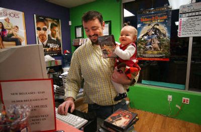 
Bill Miller holds his daughter Lauryn Miller-Williams in his video rental store, The Reel World, located on 32nd Avenue in Spokane Valley. Miller is an independent video store owner who works two jobs to keep his retail stores going. 
 (Liz Kishimoto / The Spokesman-Review)