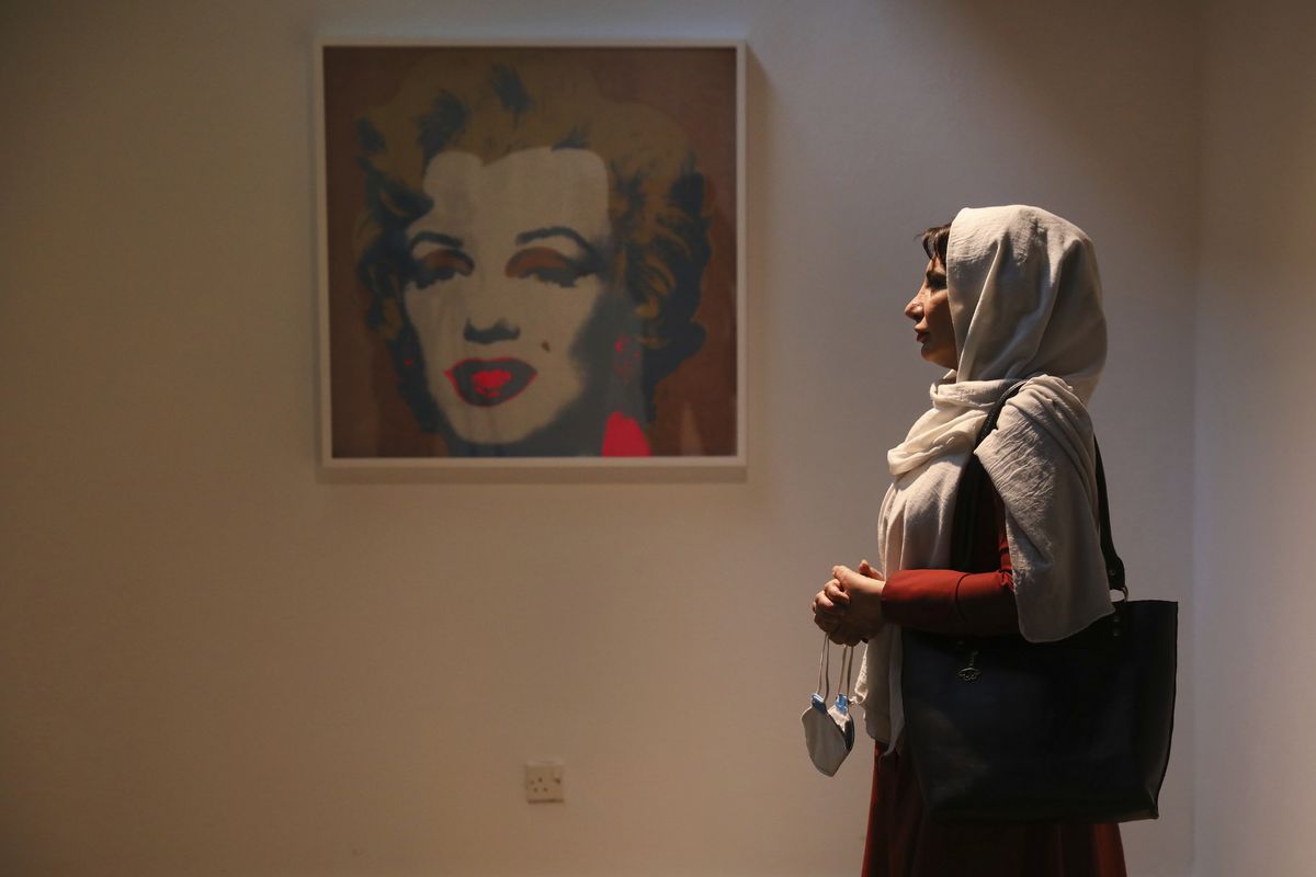 Fatemeh Rezaee, a retired teacher, stands next to a Marilyn Monroe portrait by American artist Andy Warhol on Tuesday at the Tehran Museum of Contemporary Art in Iran.  (Vahid Salemi)
