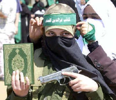 
A woman belonging to the Hamas militant group holds a toy gun and a Quran as a headband is tied on her forehead during a protest against the 1948 creation of Israel in Ein el-Hilweh refugee camp in southern Lebanon on Sunday. 
 (Associated Press / The Spokesman-Review)