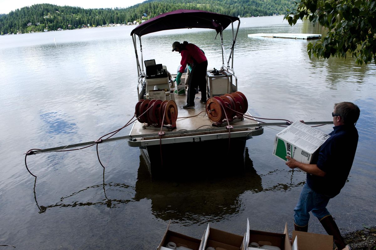 Aquatic biologist Brandon Watson loads a box of the chemical 2,4-D onto a boat equipped with outriggers designed to distribute the chemical into the water to kill Eurasian milfoil, an invasive aquatic weed, during a control effort at Newman Lake. (Tyler Tjomsland)
