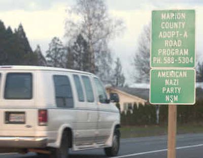 
A van passes an Adopt-A-Highway sign reading 