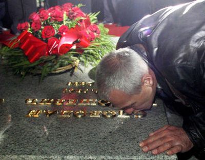 
A man kisses the grave of former Serbian leader Slobodan Milosevic during funeral services on Saturday. 
 (Associated Press / The Spokesman-Review)