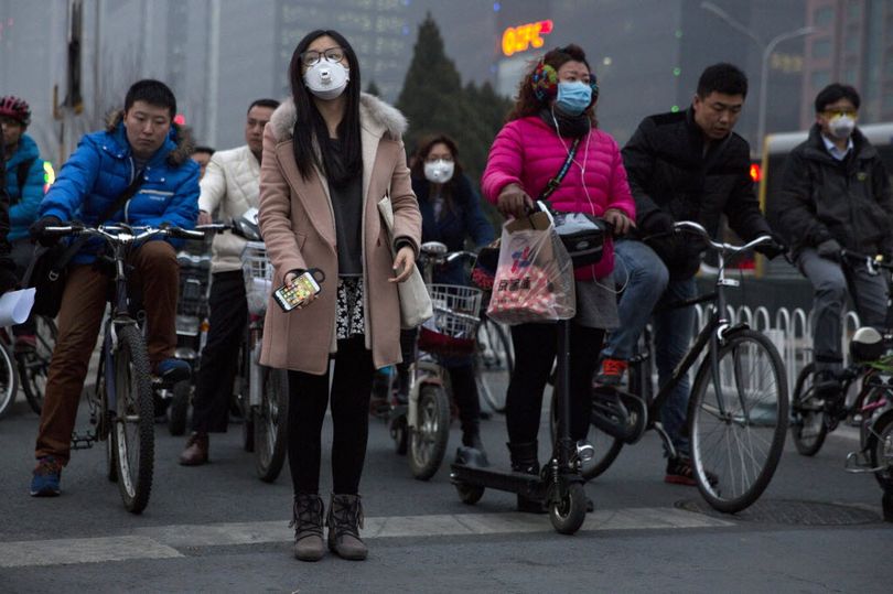 Pedestrians wearing mask against heavy pollution wait to cross a traffic junction in Beijing, Monday, March 16, 2015. The Chinese capital struggles with persistent pollution tied to rapid growth in number of cars and coal burning power plants powering the ever growing city. (AP Photo/Ng Han Guan)
