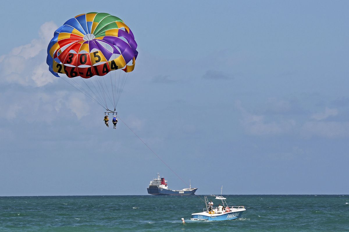 In this Sept. 24, 2012 photo, two people parasail over the Miami Beach,Fla. area. Soaring high above the ocean off South Beach, tethered only by a rope to a boat hundreds of feet below, riding in a parasail is at once exhilarating and oddly peaceful, even quiet. For millions of people, that