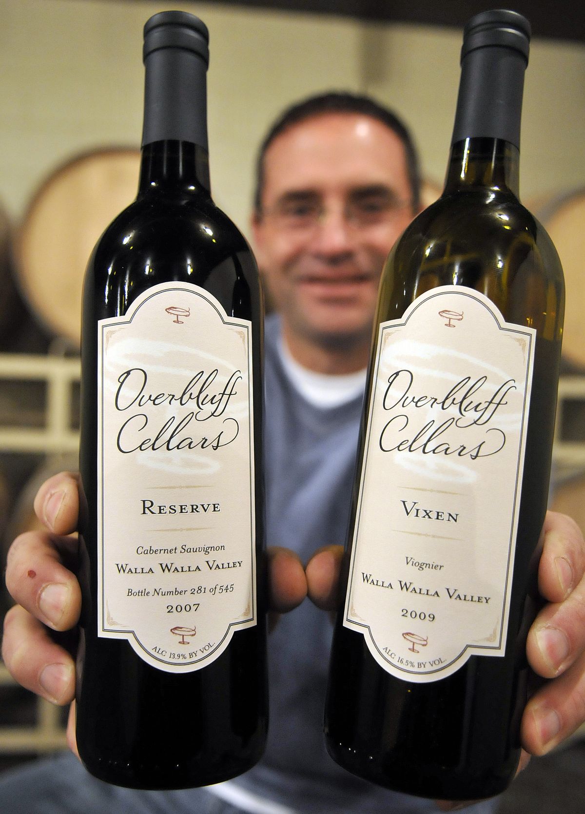 John Caudill, of Overbluff Cellars in Spokane, holds two examples of his first release vintages. (Christopher Anderson)