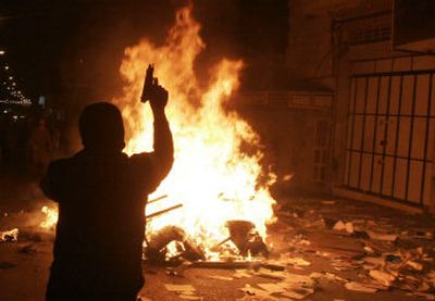 
A member of Fatah fires his pistol in the air Sunday as supporters ransack the offices of Hamas lawmakers in Hebron. 
 (Associated Press / The Spokesman-Review)