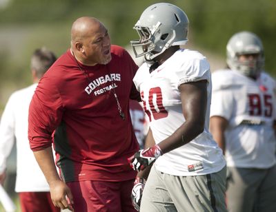 In this Aug. 6, 2014 file photo, WSU defensive line coach Joe Salave’a congratulates Kache Palacio after a play during fall football camp in Lewiston. (Tyler Tjomsland / The Spokesman-Review)