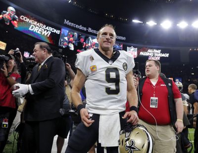 In This Oct. 8, 2018 photo, New Orleans Saints quarterback Drew Brees (9) reacts after breaking the NFL record for all-time passing yards during, the first half of an NFL football game against the Washington Redskins in New Orleans. Visitors to the Pro Football Hall of Fame can see both the football Drew Brees threw in becoming the NFL’s all-time passing yards leader and the uniform the Saints quarterback wore while making history. Mark Baker, the hall’s president and chief executive officer, holds the ball at left. (Gerald Herbert / Associated Press)