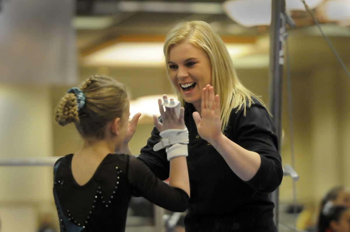 Coach Rachael Tart high-fives gymnast Tessa DePasquale after her routine on the uneven parallel bars Saturday. (Jesse Tinsley / The Spokesman-Review)