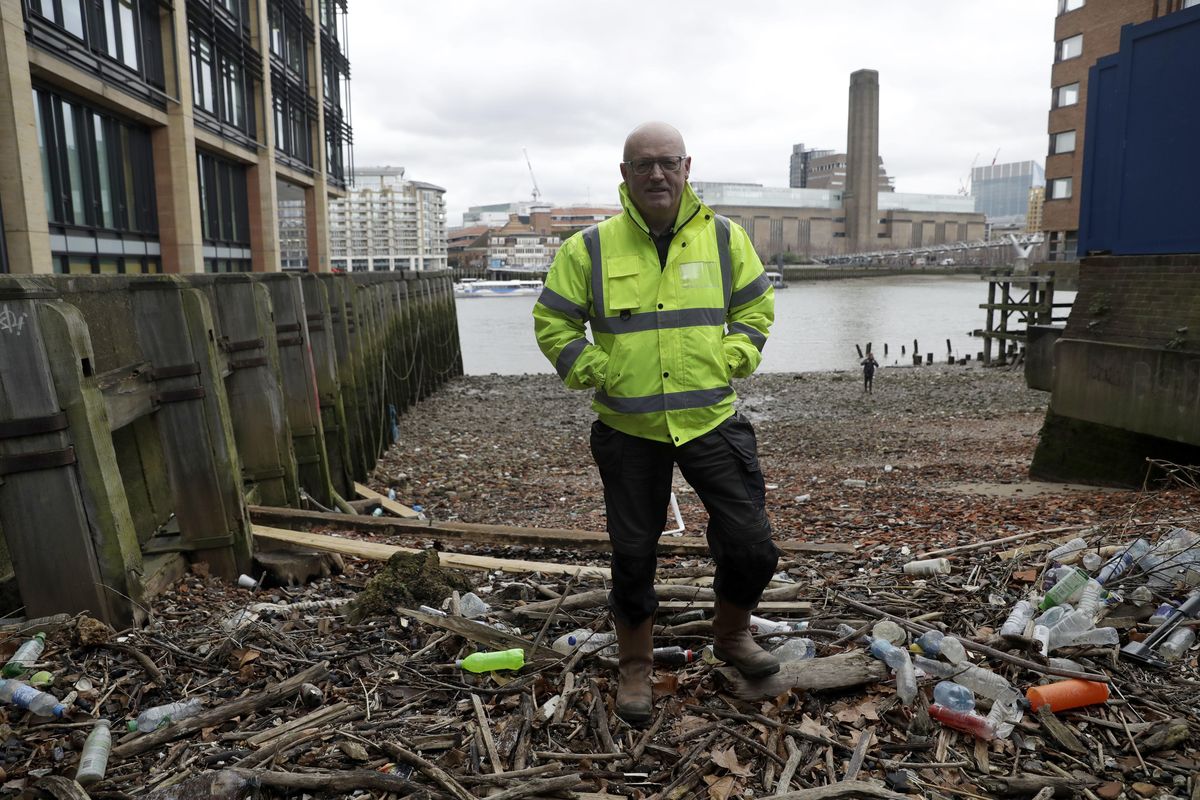Michael Byrne, a volunteer for environmental group Thames21, stands earlier this month beside plastic bottles washed up on the north bank of the River Thames in London. (Associated Press)