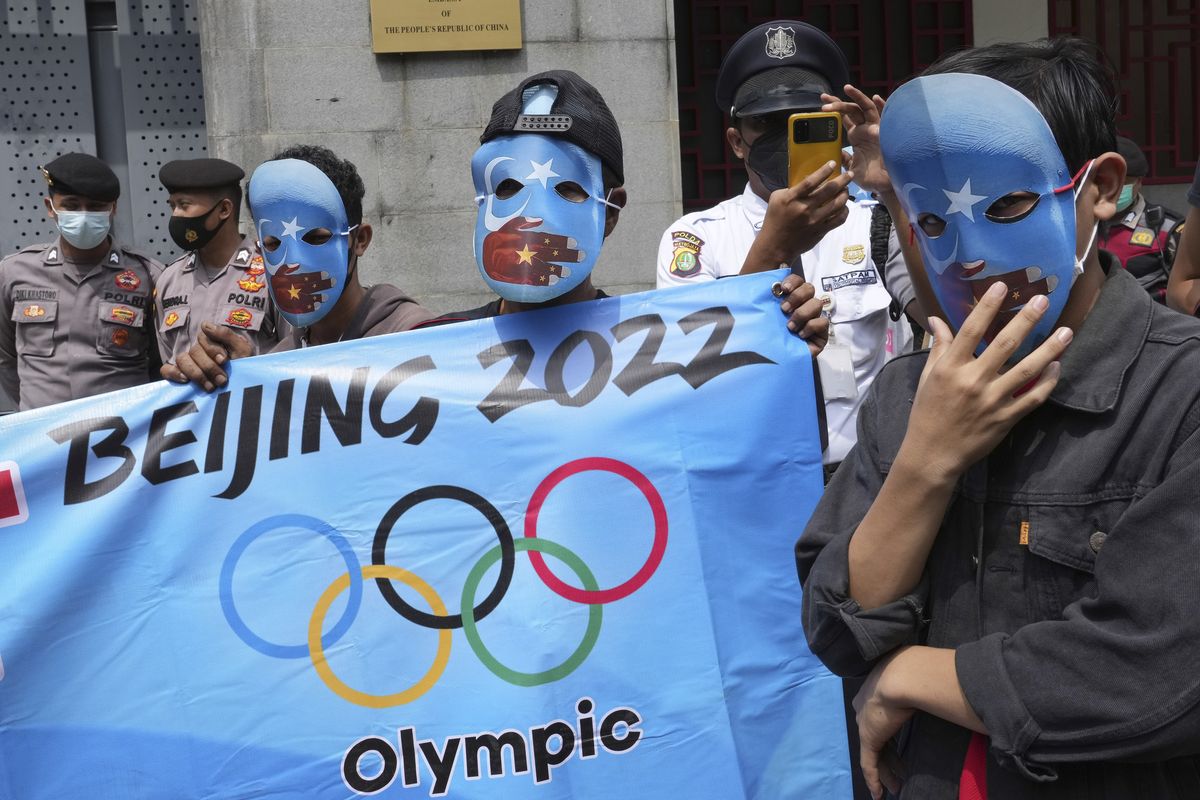 Student activists wear masks with the colors of the pro-independence East Turkistan flag during a rally to protest the Beijing 2022 Winter Olympic Games, outside the Chinese Embassy in Jakarta, Indonesia, Friday, Jan. 14, 2022. Dozens of students staged the rally demanding the cancellation of the Beijing Olympics over alleged human rights violations against Muslim Uyghur ethnic minority in China's region of Xinjiang.  (Tatan Syuflana)