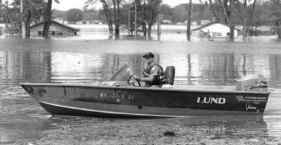 
Eric Abbott, with the Missouri Department of Conservation, operates a boat Tuesday in Missouri's Big Lake State Park, taking people to and from their flooded homes. 
 (Associated Press / The Spokesman-Review)