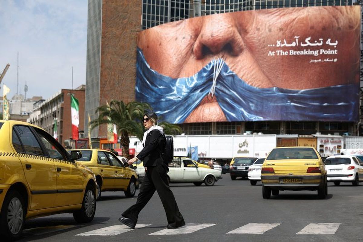 A woman walks past an anti-U.S. billboard depicting U.S. President Donald Trump and the Strait of Hormuz on Saturday in Tehran, Iran.   (Reuters )