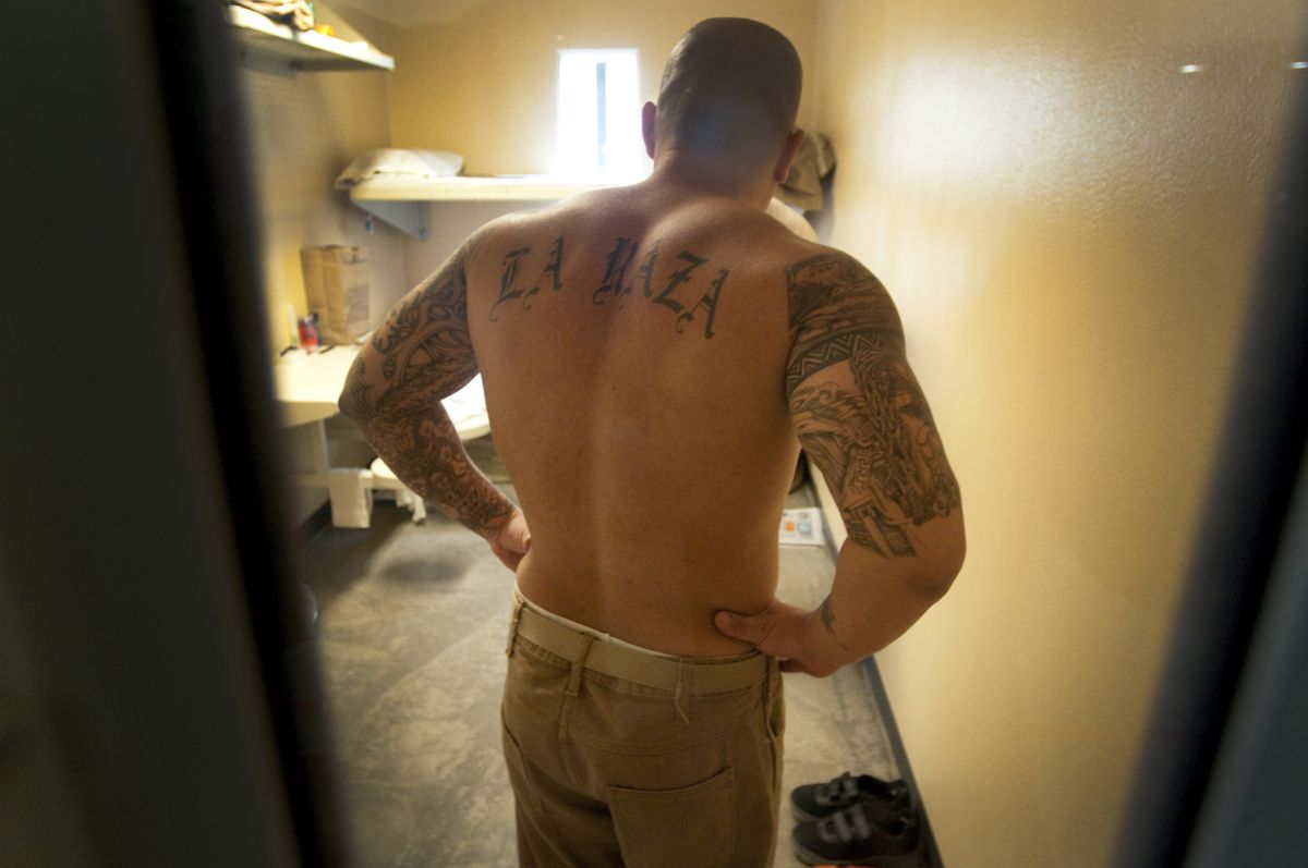 Through the door of his prison cell, Washington State Penitentiary inmate Jimmy McIntosh displays his tattoos Tuesday. The prison in Walla Walla recently built four modern housing units to help reduce gang violence against staff and other inmates.  (Photos by COLIN MULVANY / The Spokesman-Review)