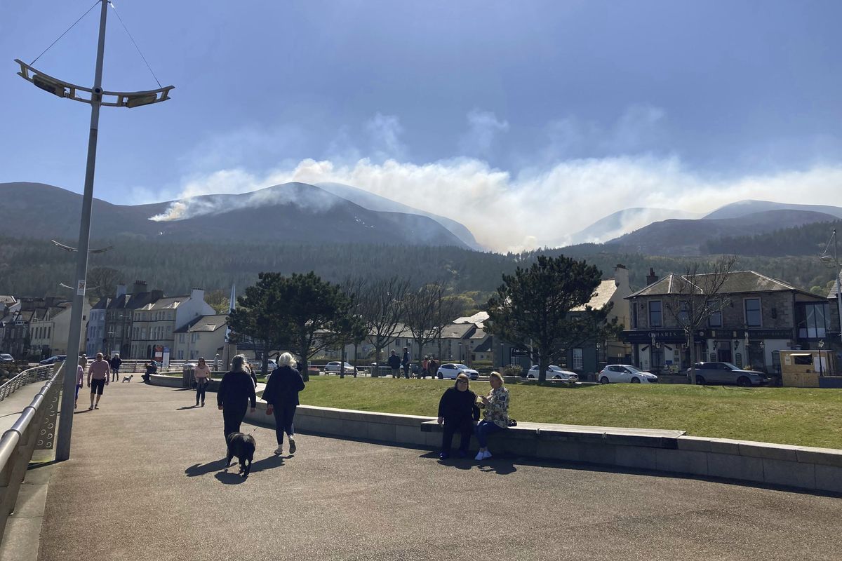 People walk with a view of smoke from the gorse fire spreading across the Mourne Mountains on Saturday in Northern Ireland.  (Rebecca Black)