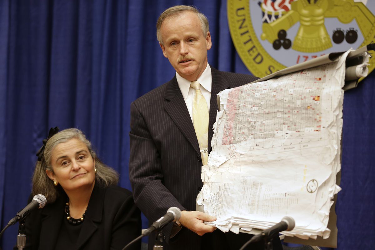 Kathryn Condon, executive director, Army National Military Cemeteries, left, listens as Patrick Hallihan, Superintendent of Arlington National Cemetery, holds up old map as an example of what had been used by the cemetery, during a news conference in Washington, Monday, Oct. 22, 2012 to present the ANC Explorer application for the cemetery. Arlington National Cemetery plans to make available to the public the detailed geospatial database it has developed over several years while overhauling its records and responding to reports of misidentified remains. The database will be available over the Internet and through a mobile phone app that visitors to the cemetery can take with them to find a specific gave anywhere in the cemetery. (Jacquelyn Martin / Associated Press)