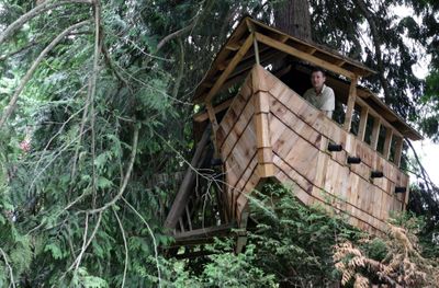 Andrew Dewberry looks out from atop his children’s treehouse in the front yard of his home in Vancouver, B.C., on July 18.  (Associated Press / The Spokesman-Review)