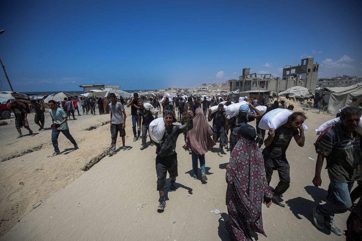 Palestinians carry bags of flour that they obtained from aid trucks that entered Gaza through the Zikim crossing point on Friday in Jabalia in the northern Gaza Strip. (Omar Ashtawy/APA Images via ZUMA Press Wire/TNS)