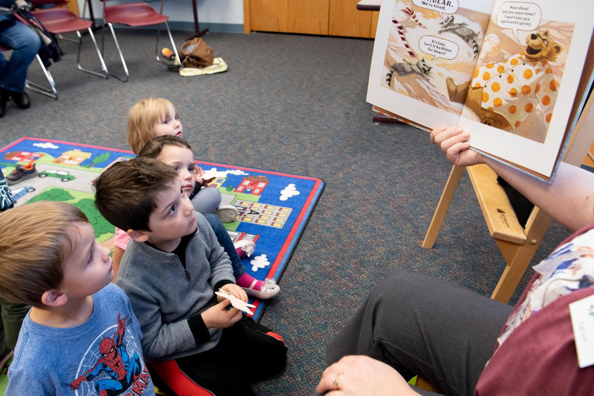 Brennan Tisch, 3, left, and Caleb Campbell, 4, listen as Spokane Public Library Youth Services Librarian Cathy Bakken, right, reads “Bedtime for Bear” Friday, Nov. 8, 2019, at Indian Trail Library during preschool story time. Local libraries are promotiong 1,000 Books Before Kindergarten, a program to help parents encourage kids to read or listen to books every day. (Jesse Tinsley / The Spokesman-Review)