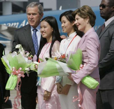 
President George W. Bush and first lady Laura Bush pose with Vietnamese women wearing traditional dresses called ao dai. 
 (Associated Press / The Spokesman-Review)