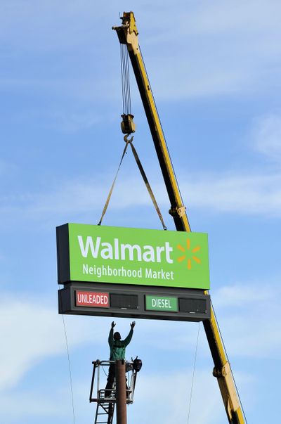 A worker stretches his arms to guide a sign into position on top of its pole Friday at the new Wal-Mart Neighborhood Market location on Old Jacksonville Road in Tyler, Texas.