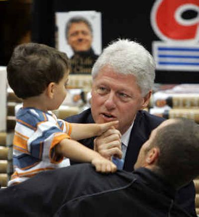 
Former President Bill Clinton chats with Colby Rosenwald, 3, in the arms of his cousin David Schwartz as Clinton signs copies of his autobiography at Costco on Wednesday in Issaquah, Wash. 
 (Associated Press / The Spokesman-Review)