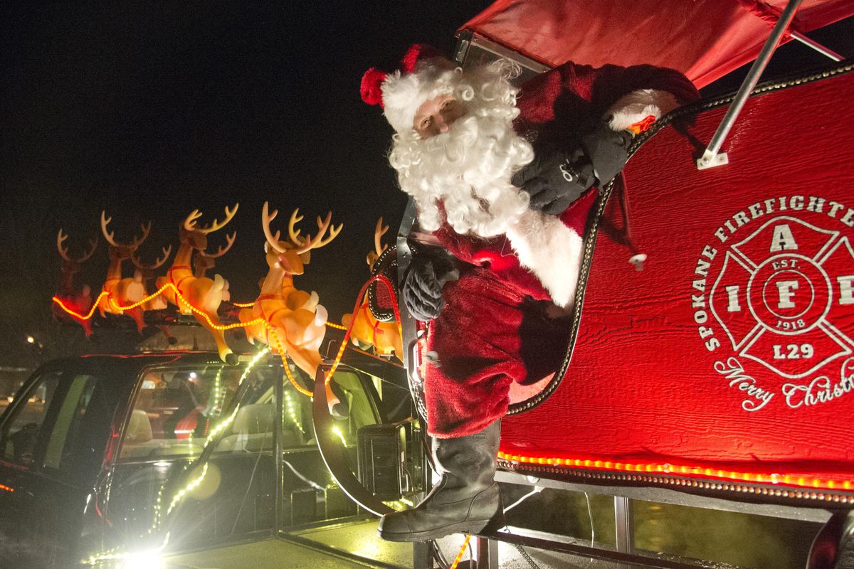 Present day:  Santa Claus (firefighter Russ Reser) poses Wednesday on the truck-mounted sleigh that the firefighters’ union uses to carry Santa through Spokane neighborhoods.   The truck-mounted Santa has been going on tours around the city for more than 50 years. (Jesse Tinsley / The Spokesman-Review)