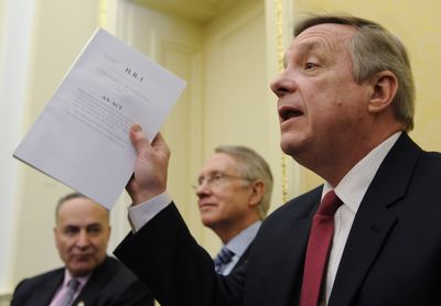 Sen. Richard Durbin, D-Ill., right, accompanied by Sen. Charles Schumer, D-N.Y., left, and Senate Majority Leader Harry Reid, of Nevada, holds a copy of the stimulus bill passed by the House of Representatives as he speaks to reporters on Capitol Hill on Thursday.  (Associated Press / The Spokesman-Review)