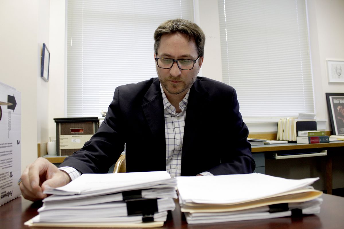 Carl Macpherson, executive director at Metropolitan Public Defender, examines the file in a double murder case that was recently pushed back for trial in his office in Portland on Thursday.  (Gillian Flaccus)