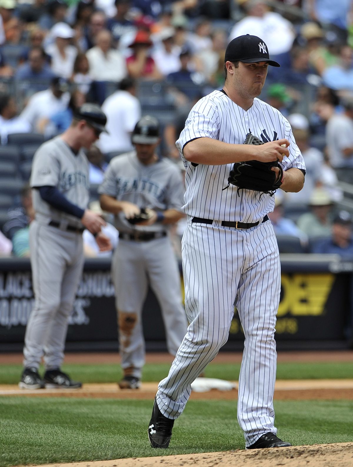 Seattle Mariners Dustin Ackley, center, talks with third base coach Jeff Datz as New York Yankees starting pitcher Phil Hughes walks back to the mound after Ackley hit an RBI triple in the third inning of a baseball game on Wednesday, July 27, 2011 at Yankee Stadium in New York. The Mariners won 9-2. (Kathy Kmonicek / Fr170189 Ap)