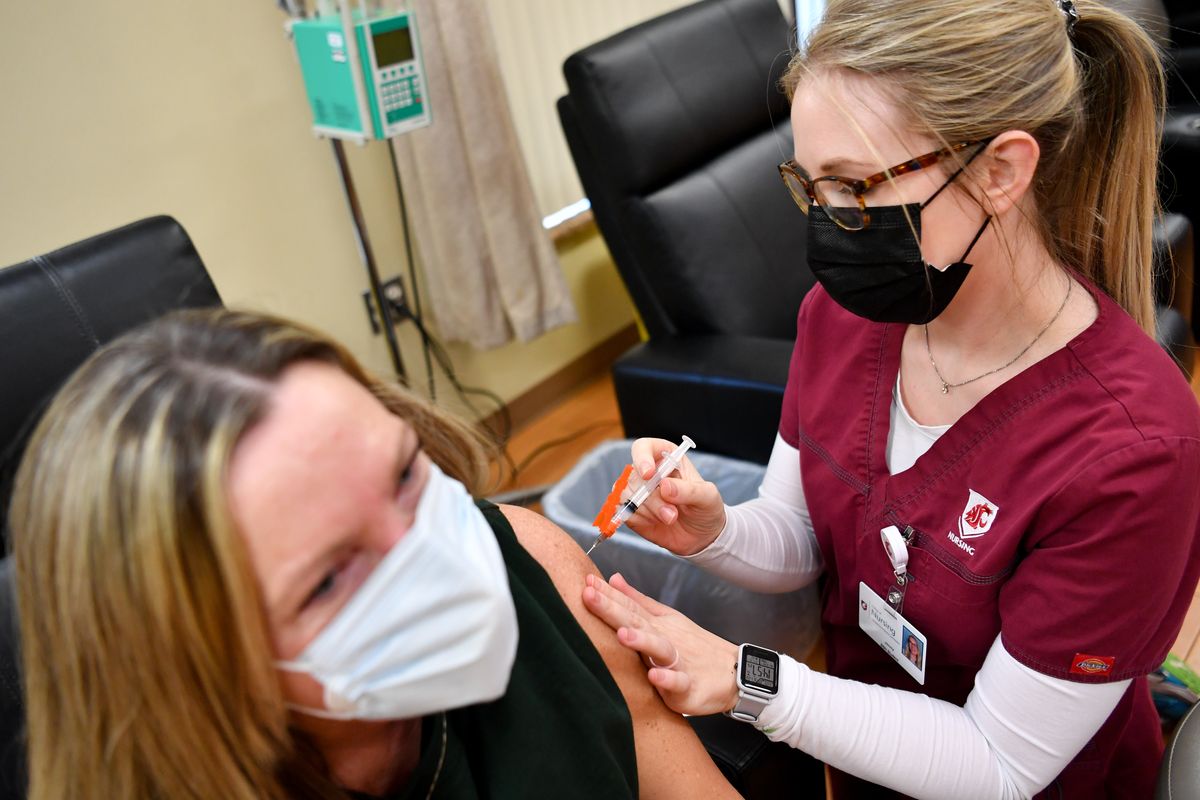 Lisa Pederson receives a COVID-19 vaccine from WSU nursing student Jenny Richardson on Jan. 22 at Summit Cancer Centers in Spokane. Students have had their training interrupted in part by the pandemic, which is putting a toll on professionals who’ve worked the frontlines since March 2020, according to a new state survey.  (Tyler Tjomsland/The Spokesman-Review)