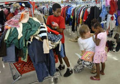 
Michelle Gardner  and her 4-year-old daughter, Dinah,  discuss whether Dinah may get a book in addition to school clothes, while Gardner's  son Nathanael, 8,  stands by the family's cart Monday at Value Village in Spokane during the thrift store's  Labor Day sale.
 (Holly Pickett / The Spokesman-Review)