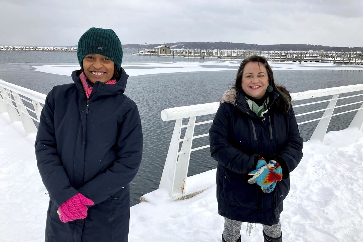 Activists Tyasha Harrison, left, and Holly T. Bird pose along the Grand Traverse Bay waterfront in Traverse City, Mich., Feb. 13, 2021. They are among local residents who have criticized a county commissioner for displaying a gun during an online meeting. The official
