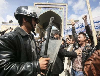 An Afghan police officer pushes a counterprotester during a demonstration in Kabul, Afghanistan, on Wednesday by women protesting a controversial new marriage law.  (Associated Press / The Spokesman-Review)