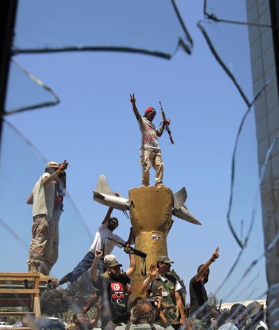 Rebel fighters celebrate as they stand on top of a monument inside the main Moammar Gadhafi compound in Bab Al-Aziziya in Tripoli, LiIbya, on Wednesday. The rebels say they have now taken control of nearly all of Tripoli, but sporadic gunfire could still be heard Wednesday. (Associated Press)