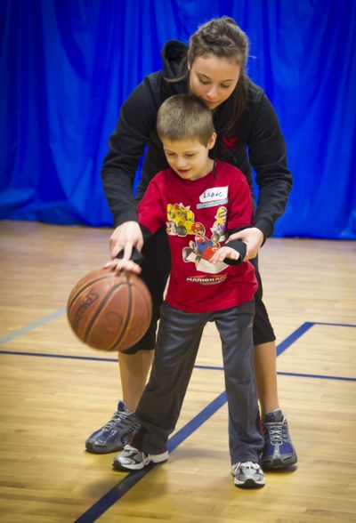 At the Warehouse in North Spokane Feb. 12, volunteer Jamie Palmer helps Isaac Mitchell, 5, with his dribbling skills. The Northwest Autism Center has launched a basketball program for children with autism. The goal is to improve basketball skills, but more importantly to help them learn the social mysteries of team sports. (Colin Mulvany)