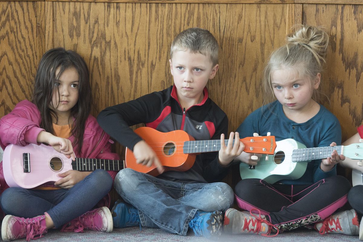 Millwood kindergarteners, from left, Patricia Gabino, Sammy Jones and Jayleeanna Lincoln-Jones strum their ukuleles in a new program with music teacher Nathan Westlund earlier this month. Westlund saw how kids loved to get their hands on the tiny instruments, so he bought a bunch and started teaching the class. (Jesse Tinsley / The Spokesman-Review)