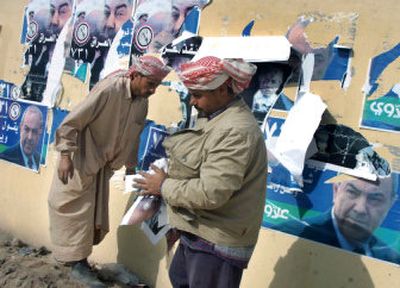 
Iraqi workers replace defaced campaign posters for the Iraqi National list with posters showing former Prime Minister Ayad Allawi on Sunday. Allawi claimed he survived an assassination attempt in Najaf, Iraq, on Sunday. 
 (Associated Press / The Spokesman-Review)