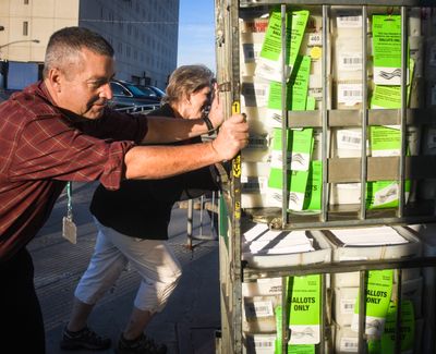 Mike McLaughlin, elections manager and Kit Anderson, elections supervisor, right, of the Spokane County Elections Office, roll a cart weighting 840 pounds with ballots into a Ryder truck headed to the post office on Oct. 18, 2018.  (DAN PELLE)