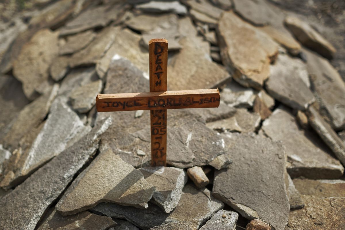 In this photo taken Monday, June 5, 2017, a wooden cross marks the grave of South Sudanese refugee James Malish’s mother Joyce Doru, on an isolated patch of land designated by Ugandan officials on the edge of Bidi Bidi, the world’s largest refugee settlement, in northern Uganda. Refugees sheltering here are having to learn new ways of life and death, and when they die their families face a dilemma: bury them without the traditional customs, or carry them home and face war again. (Ben Curtis / Associated Press)