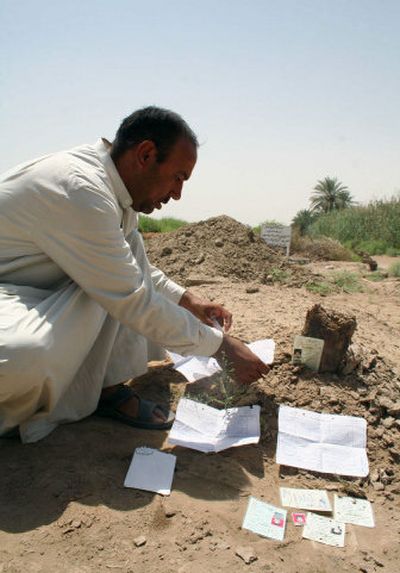 
Mohammed al-Janabi, uncle of an Iraqi girl raped and killed in March, allegedly by American soldiers, displays IDs and death certificates on his niece's grave in  July  in Mahmoudiya,  Iraq. 
 (File Associated Press / The Spokesman-Review)