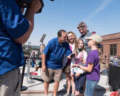 KREM-TV meteorologist and anchor Tom Sherry, left, interviews a family who was downtown in Spokane to view an eclipse in August 2017. Sherry announced his retirement, effective in early March, after a career spanning four decades.  (Jesse Tinsley/The Spokesman-Review)