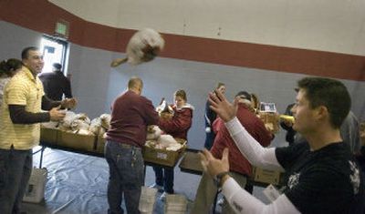 
Kenny Stoner, left,  prepares to receive a flying turkey from Frank Cottongin at the Spokane Salvation Army on Tuesday. An estimated 6,000 turkey and food packages from Second Harvest Inland Northwest were distributed. The daylong event is the largest holiday distribution in the area with more than 200 volunteers. Stoner and Cottongin were part of a  group of air traffic controllers from Fairchild Air Force Base that volunteered for the day. 
 (Christopher Anderson / The Spokesman-Review)